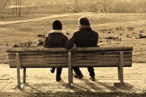 two people sitting on a park bench